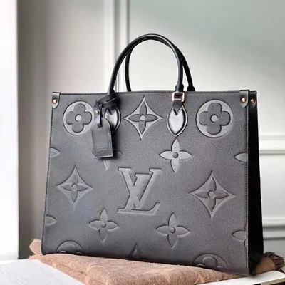 A grey embossed-monogram leather tote bag with rolled handles and a hanging name tag